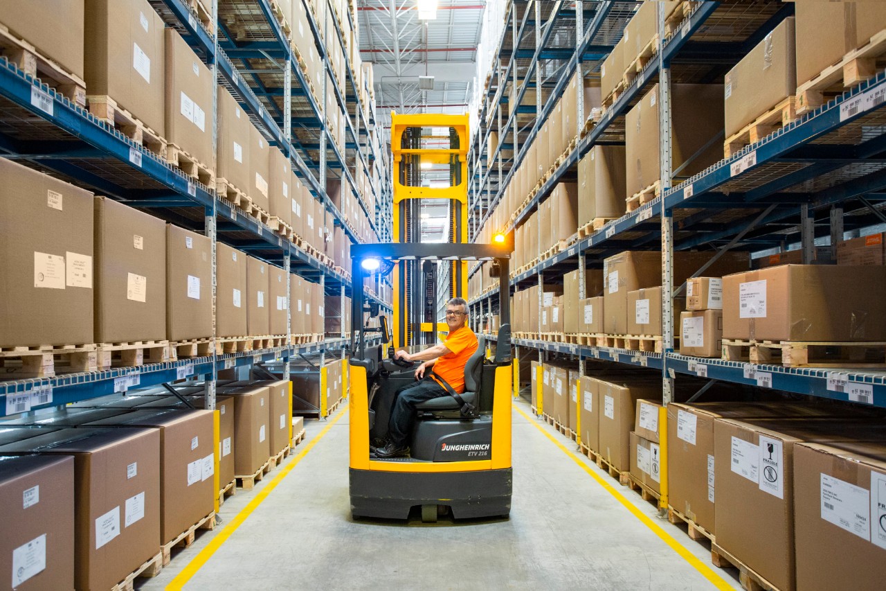 Warehouse combilift moving down a fully stocked aisle in a distribution centre